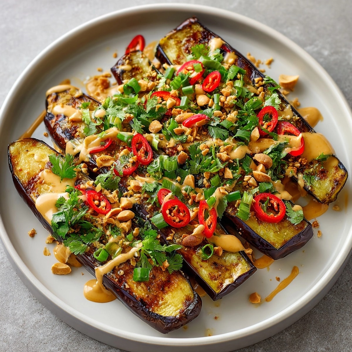 Grilled Thai Peanut Eggplant: Tender, smoky slices drizzled in creamy peanut sauce.