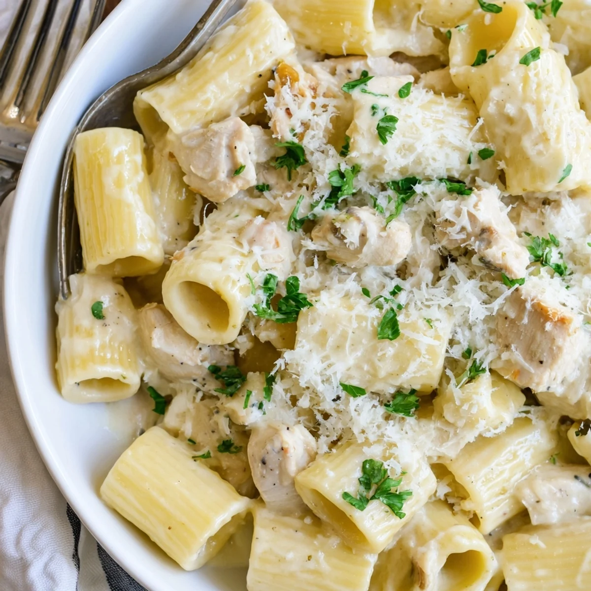 Creamy Garlic Parmesan Chicken Rigatoni drizzled with olive oil and fresh parsley highlights comfort food.