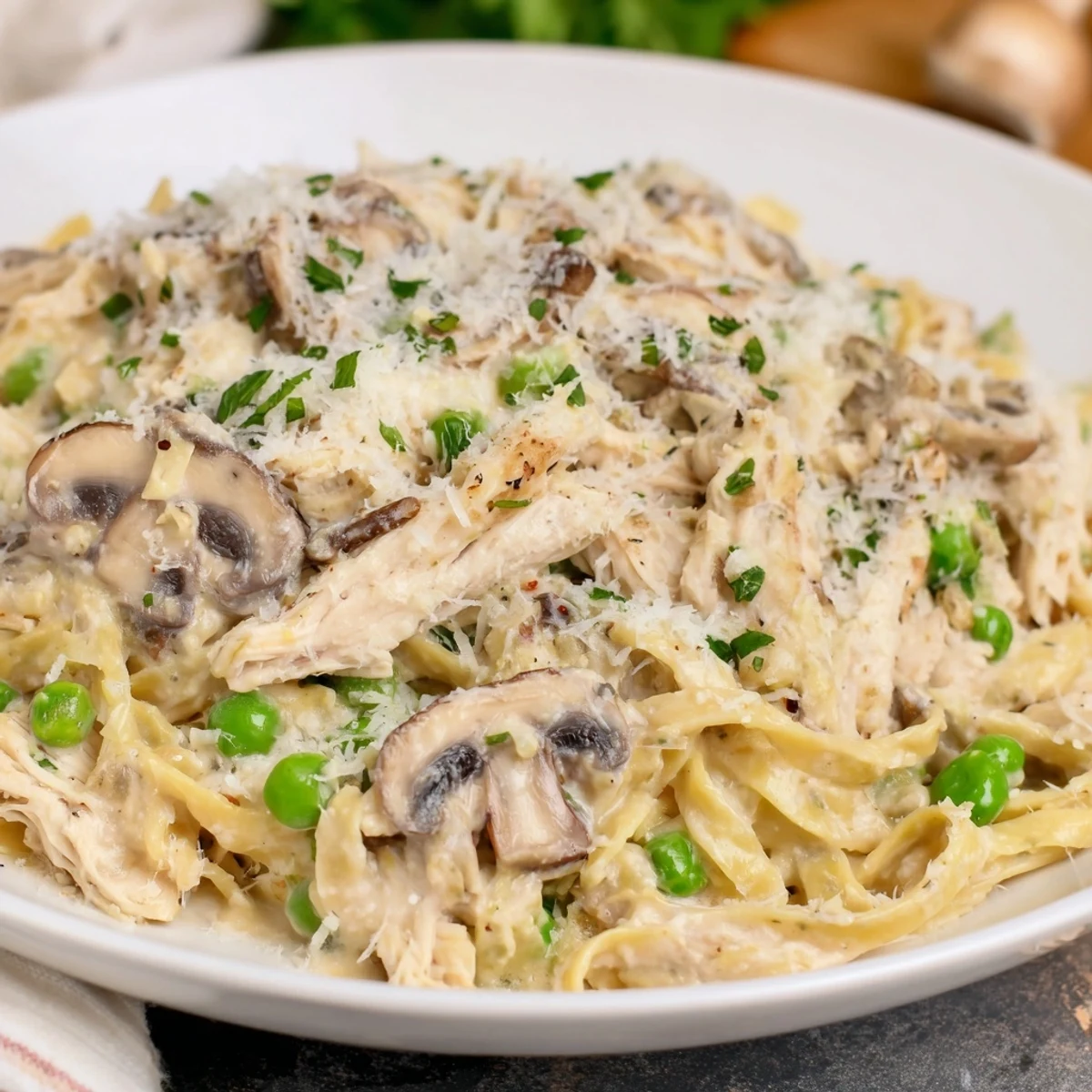 A close-up of a steaming bowl of Creamy Chicken Alfredo, garnished with fresh parsley.