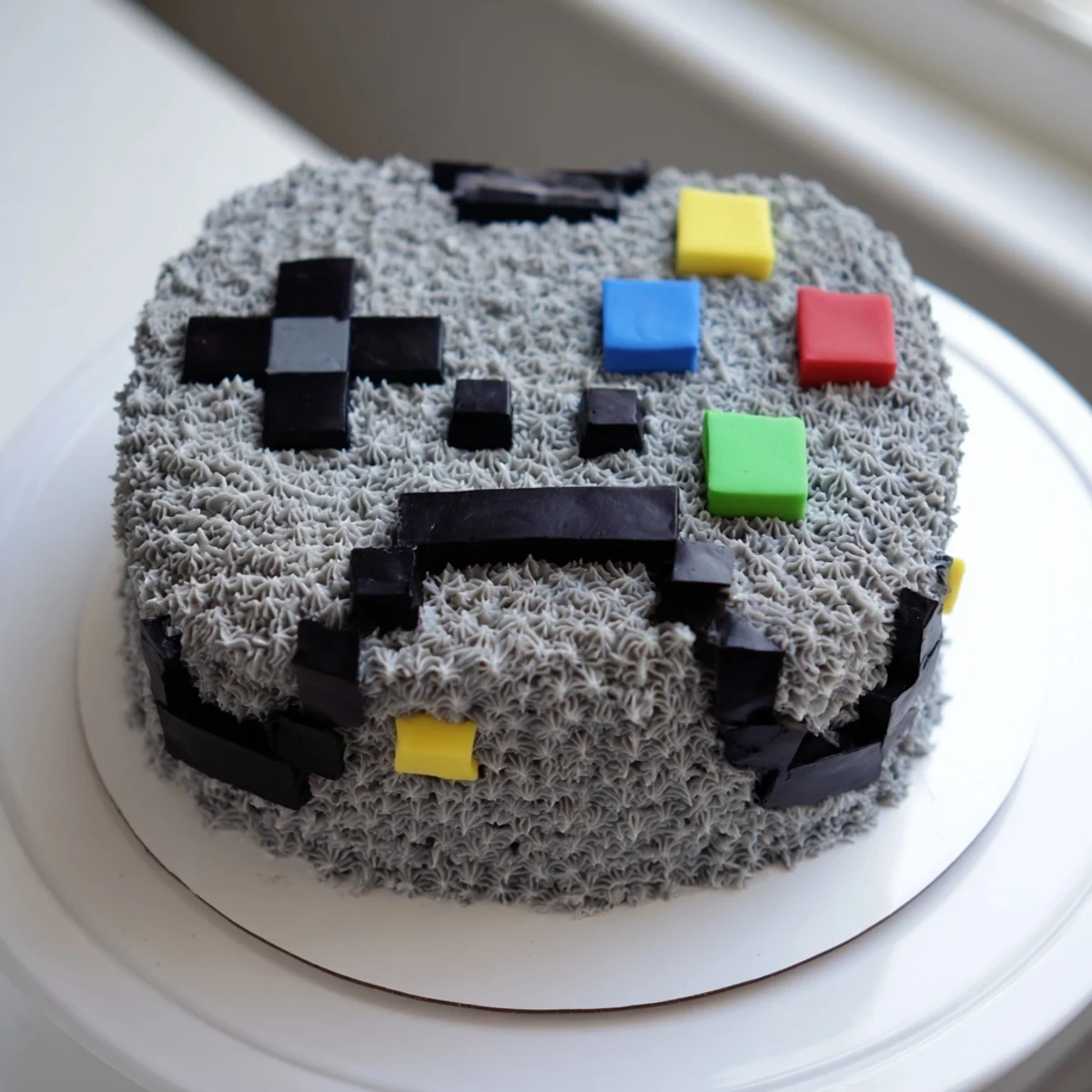 A visually striking Pixel Video Game Controller Cake, ideal for a gamer, features precisely designed pixelated buttons.