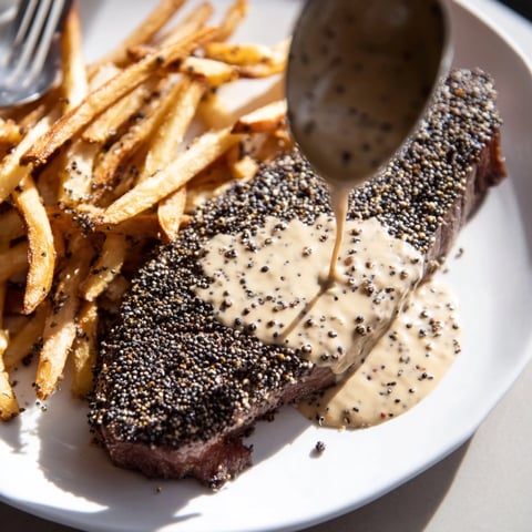 Juicy Classic Peppercorn Ribeye drizzled with creamy sauce and served alongside crispy fries.  