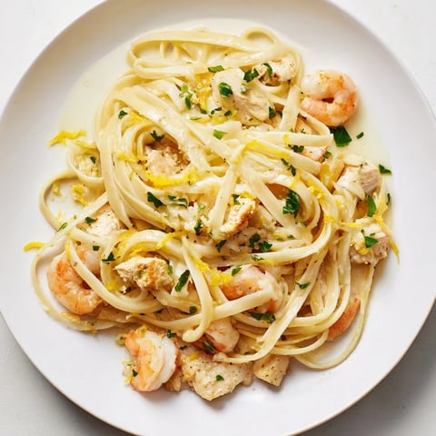 Plated Lemon Garlic Shrimp & Chicken Pasta glistens with buttery lemon-garlic sauce and fresh parsley garnish.