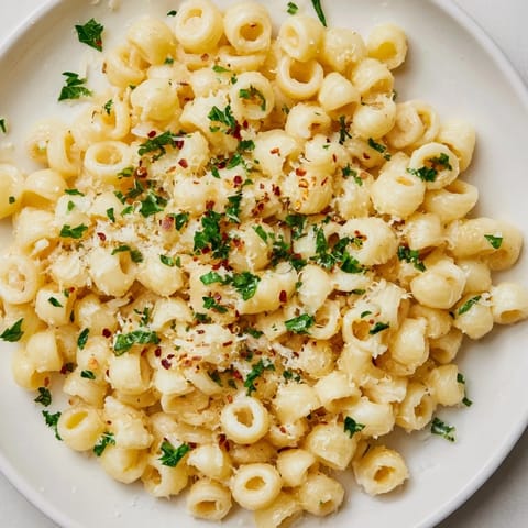 A close-up of steaming ditalini pasta, coated in a rich, creamy garlic sauce, prepared for a quick meal.