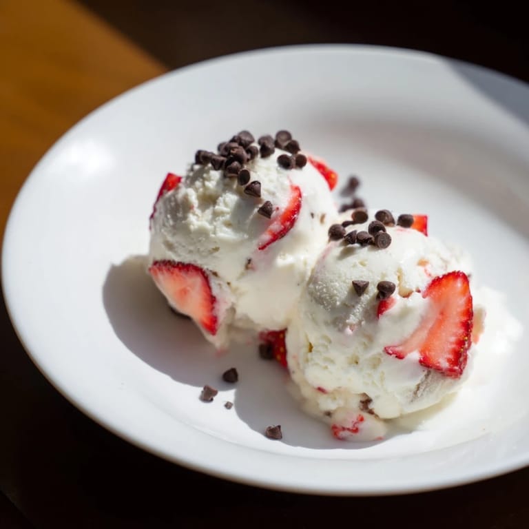 A close-up of thick, homemade cottage cheese ice cream, swirled with chunks of fresh berries.