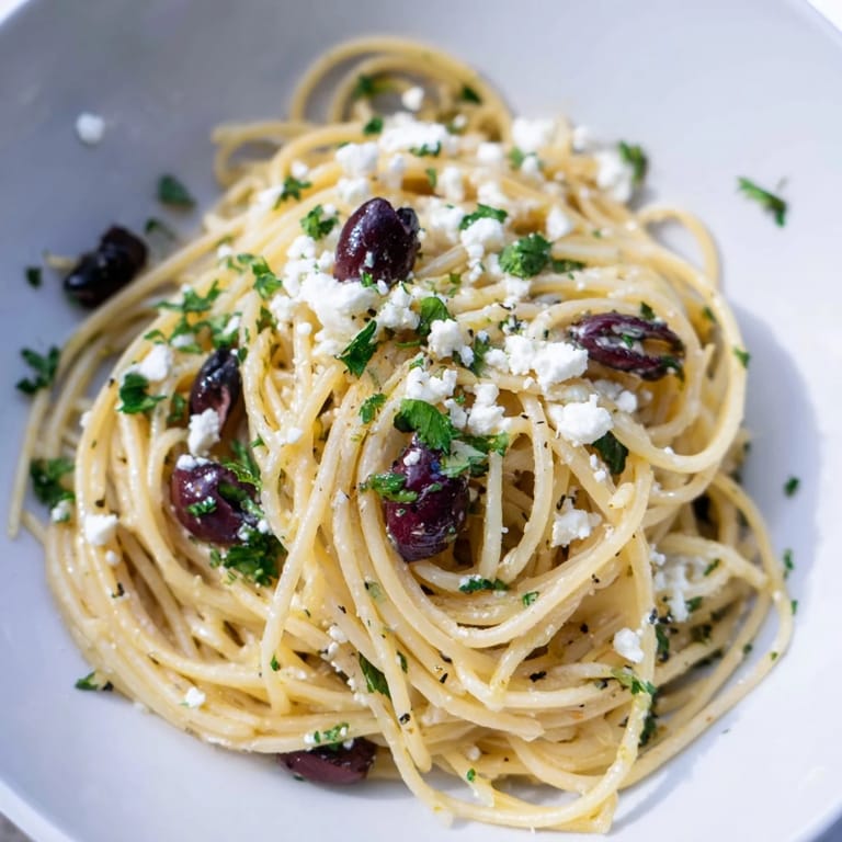Close-up of Greek Chicken Spaghetti with vibrant red cherry tomatoes, fresh parsley, and a drizzle of extra-virgin olive oil.
